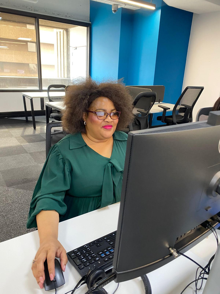 Spero team member in a green blouse working at a desktop computer