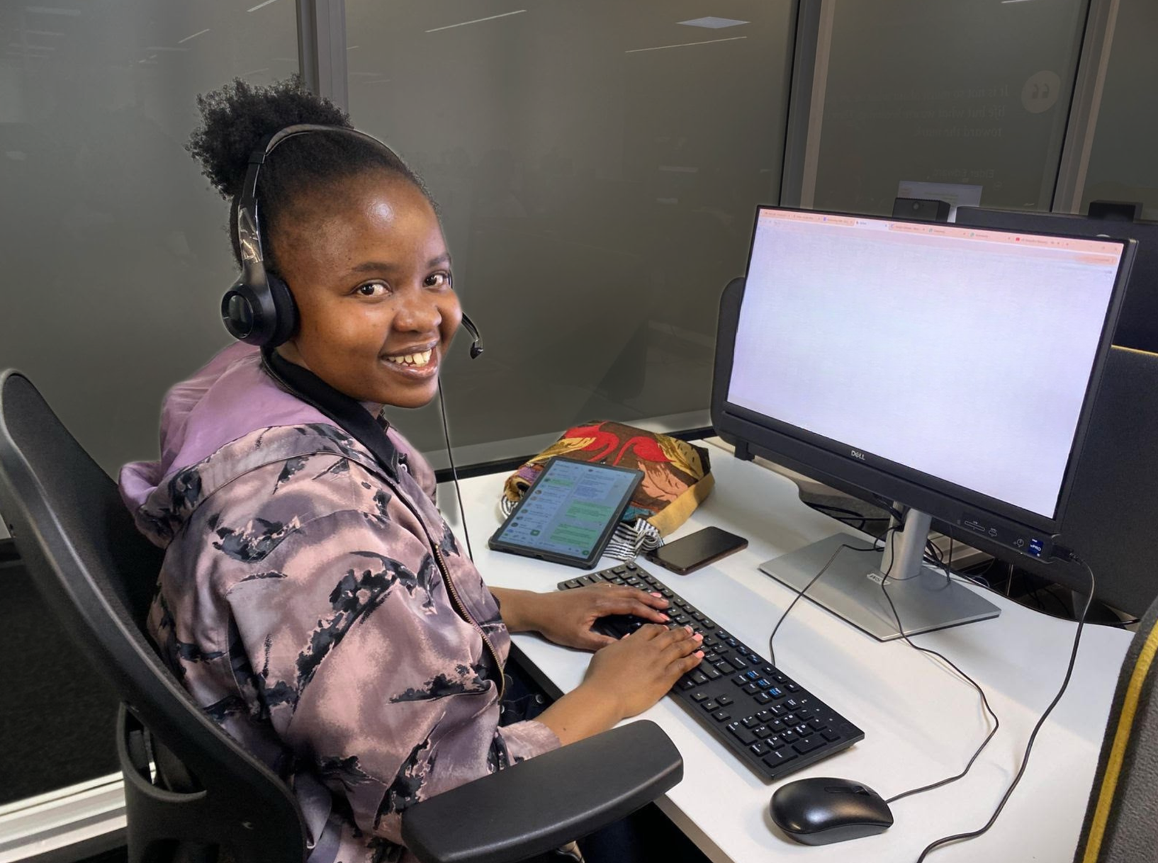 Spero graduate smiling at her desk with a headset on
